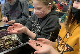 three students holding worms
