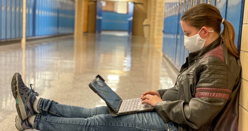 student working on laptop in hallway