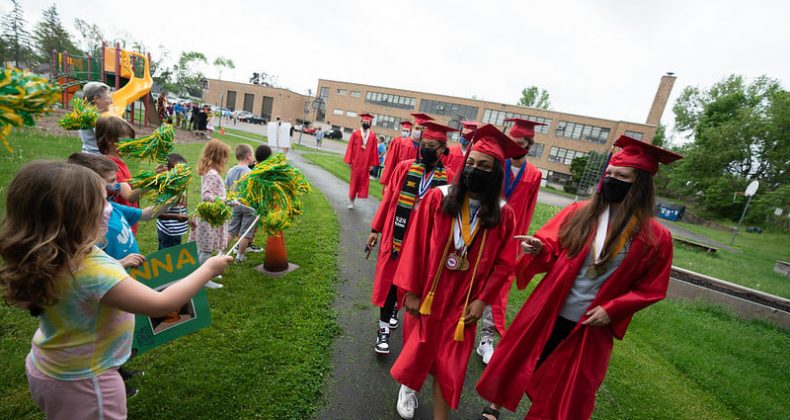 high school graduates walk near young students