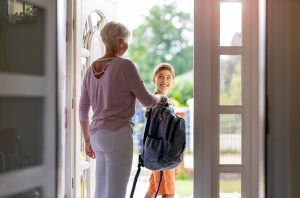 Mother and son with backpack in entrance hall