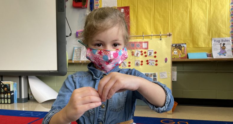 young student with hands together wearing mask