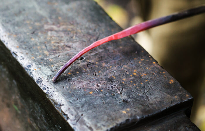 Red hot glowing steel rod on anvil close up