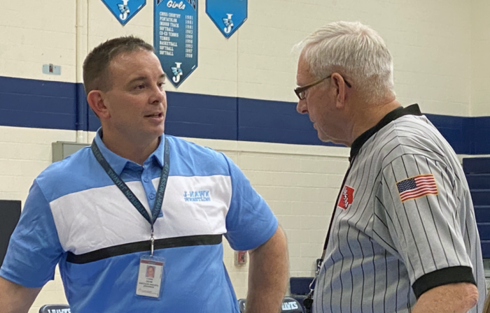 Chris Deam talks with a wrestling official before a match.