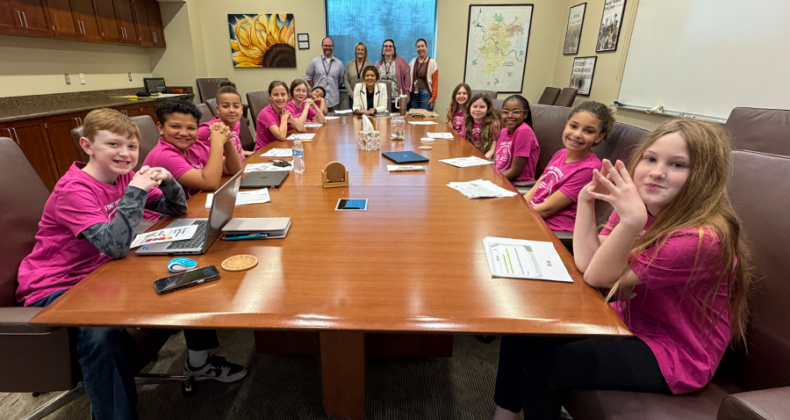 Students in pink shirts are meeting with the Superintendent of schools.