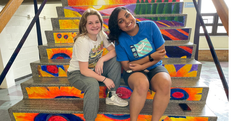 Students sitting on painted stairway.