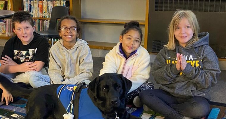 Students doing yoga with therapy dog