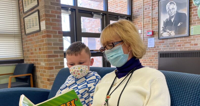 employee reading book to student