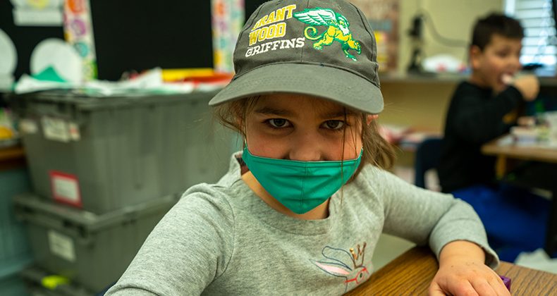 student at desk wearing mask and grant wood hat