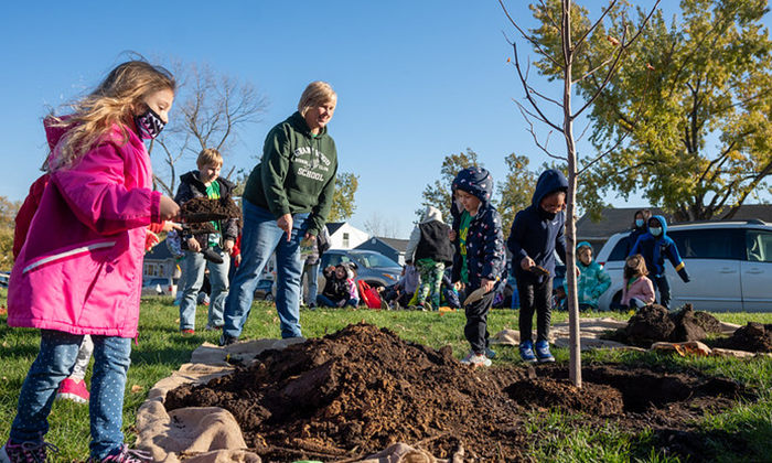 students helping plant tree outside grant wood elementary school