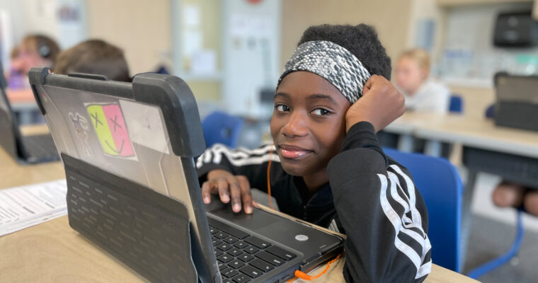 Student smiling at camera with laptop