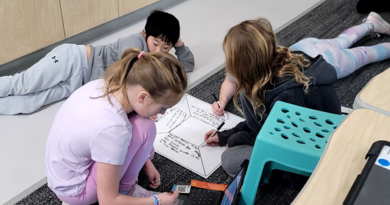 Four Maple Grove students work on a diagram to discuss their learning.