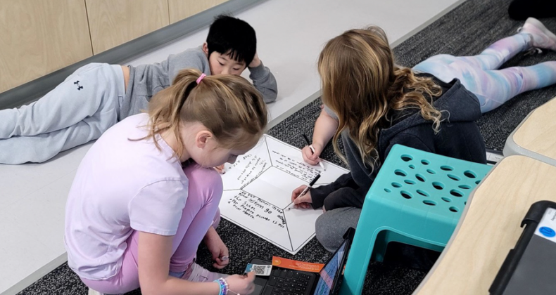 Four Maple Grove students work on a diagram to discuss their learning.