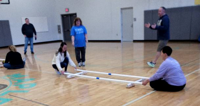 Maple Grove staff in the gym sitting together learning a new skill.