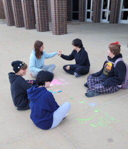 Students enjoy using sidewalk chalk outside the school.