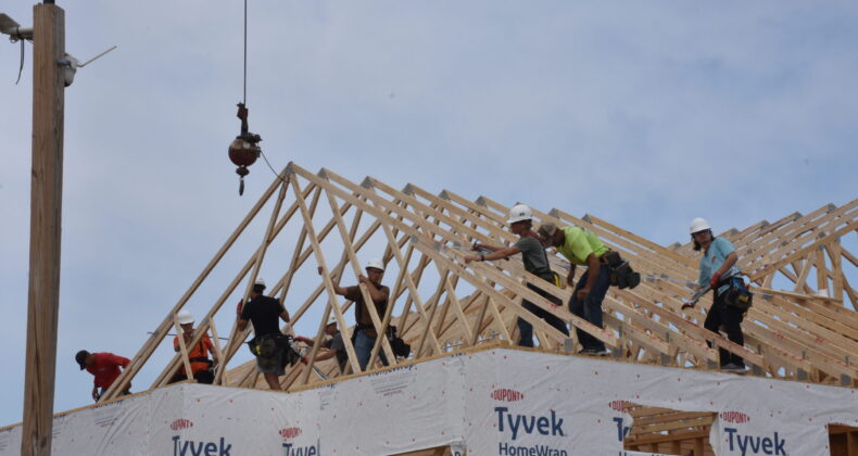 Students work to set the roof rafters on this year's house
