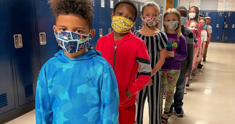 students wearing masks standing in line in hallway