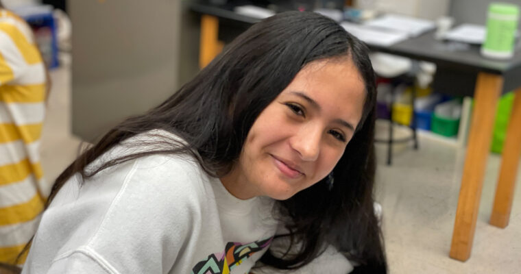 student drawing smiling at camera