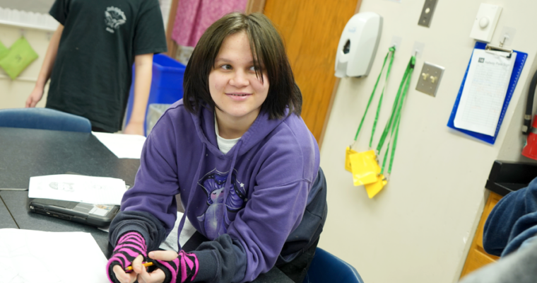 A Harding student wearing a purple sweatshirt looks to a teacher.