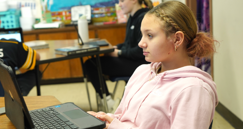 A student sitting in front of a laptop computer listens to learning.