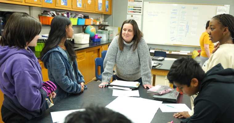 A Harding teacher works with a group of students around a table in a classroom.