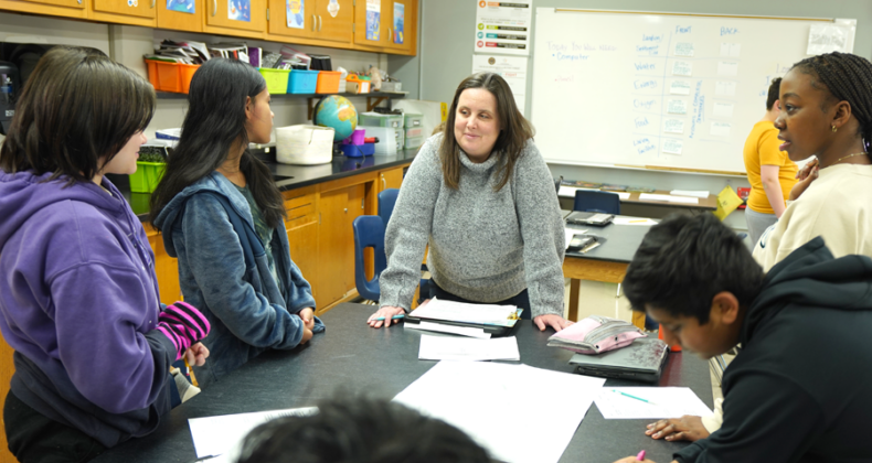 A Harding teacher works with a group of students around a table in a classroom.