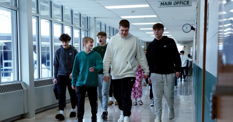 Five Harding boys walk down the hallway in various color sweatshirts.