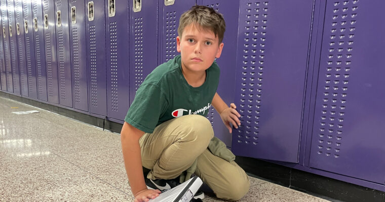 Student kneeling in front of lockers