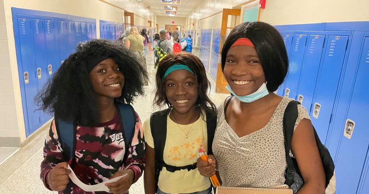 three students smiling together in hallway