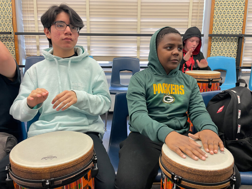 Two students playing the drum